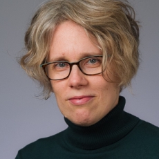 Image of Lila Ellen Gray with short blonde hair, glasses, and a green and black turtleneck sweater
