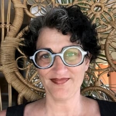 Image of Susan McDonic with short, curly black hair and glasses